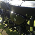 AJS 16MS - 1957 - Side Panel with Badge, Footrest, Shock Absorber, and Chain Guard.